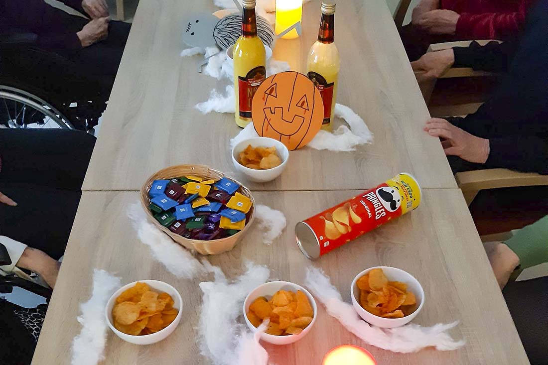 Tisch mit Halloween Dekoration, Schalen mit Chips und Süßigkeiten, Eierlikör und LED-Kerzen